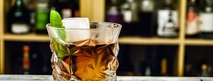 glass-of-bourbon-with-lemon-zest-at-bar